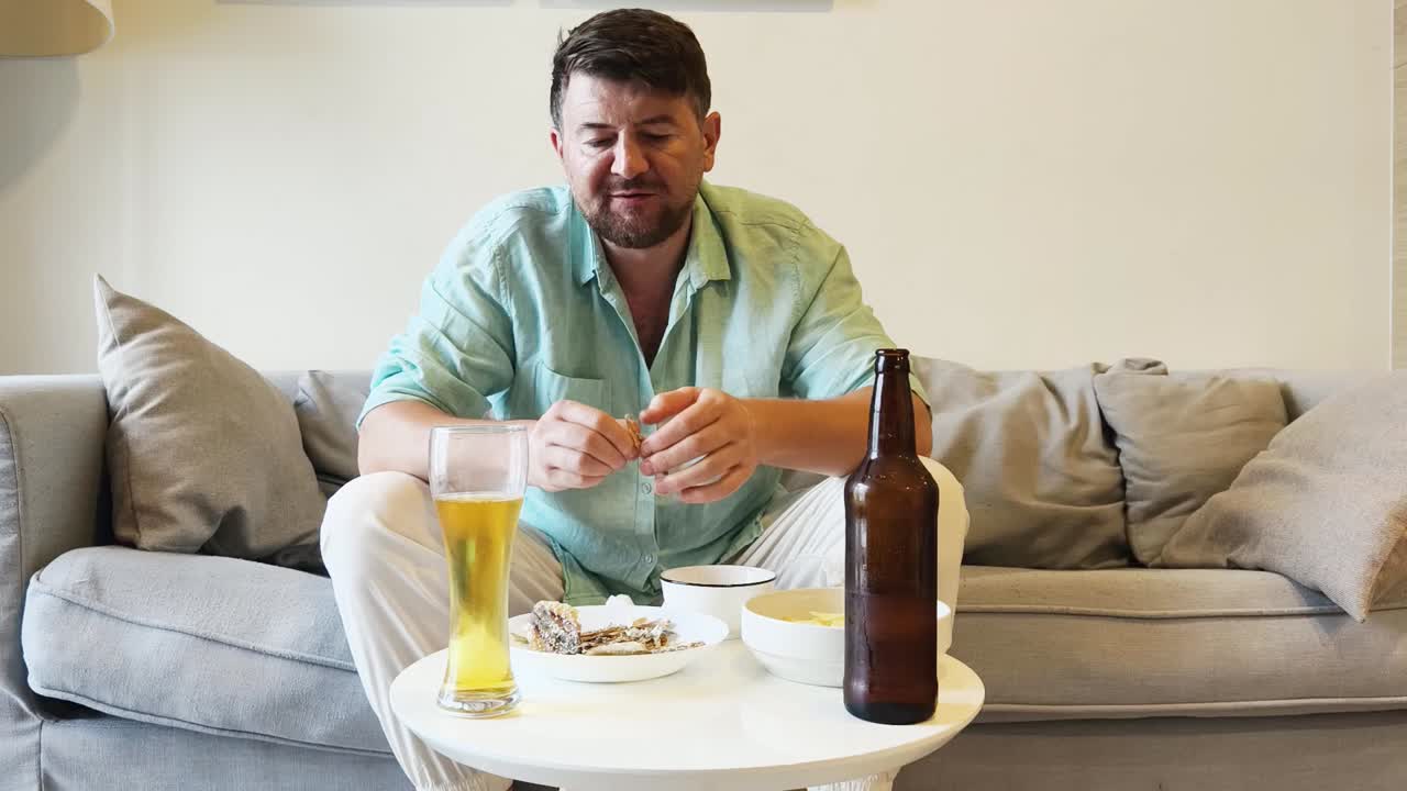 Man relaxing on sofa with beer and food