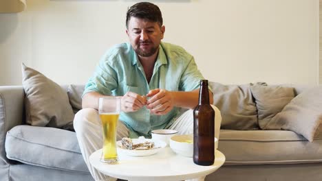 man relaxing on sofa with beer and food