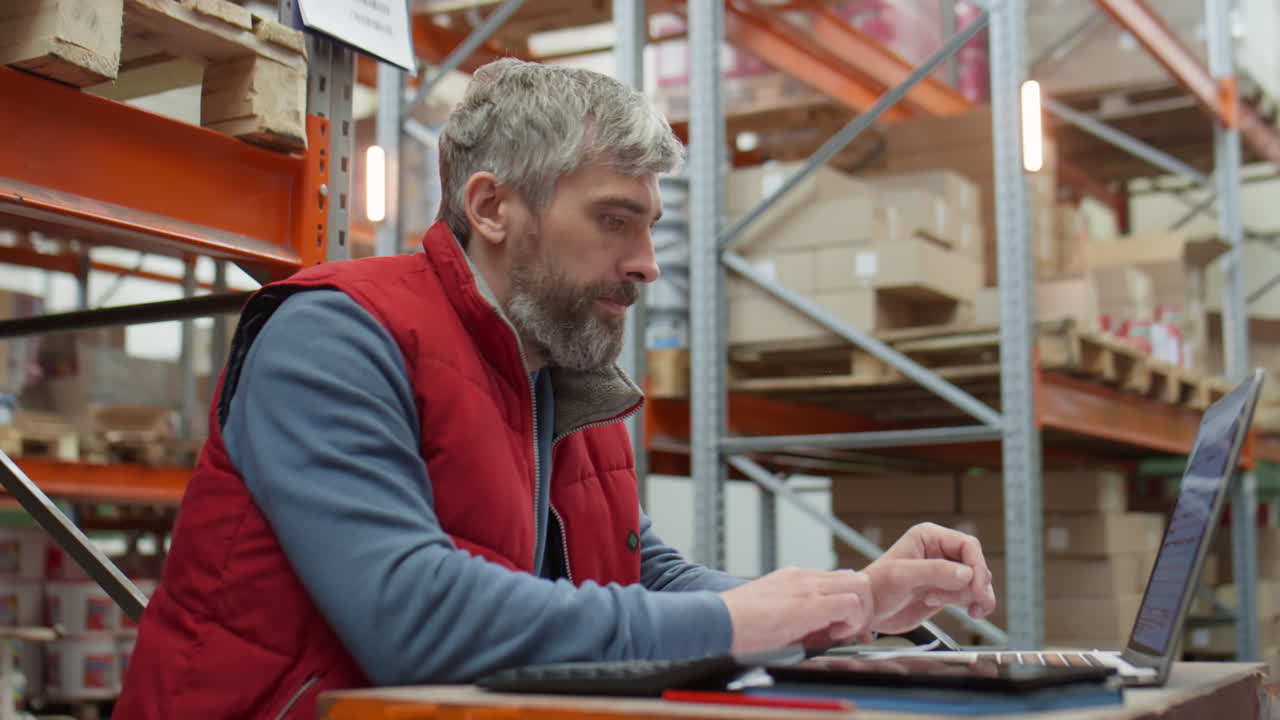 Mid-Aged Manager Working on Laptop in Warehouse