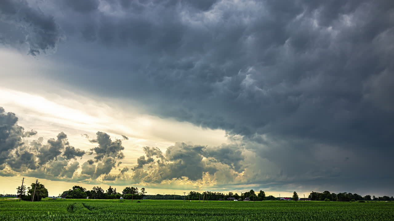 Dramatic, powerful thunderstorm clouds rolling over a green field and rural landscape