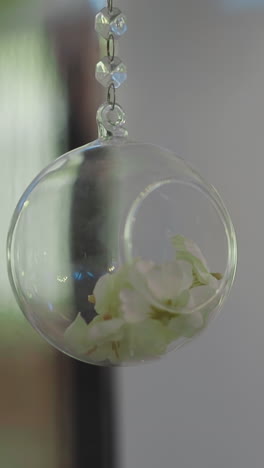 decorative element of glass ball with dry flower petals hangs in elegant room extreme closeup. stylish ornament for wedding celebration. interior design