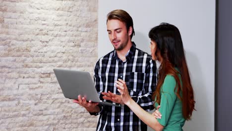 ejecutivos masculinos y femeninos discutiendo sobre la computadora portátil