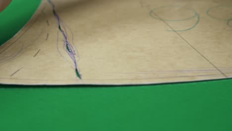 empleado dibuja parte en tela verde con tiza en el taller
