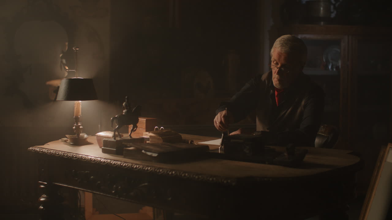 Old passionate man writes a letter in his office at night