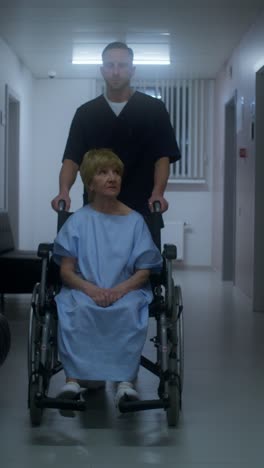 enfermera ayudando a un paciente anciano en silla de ruedas en el pasillo del hospital