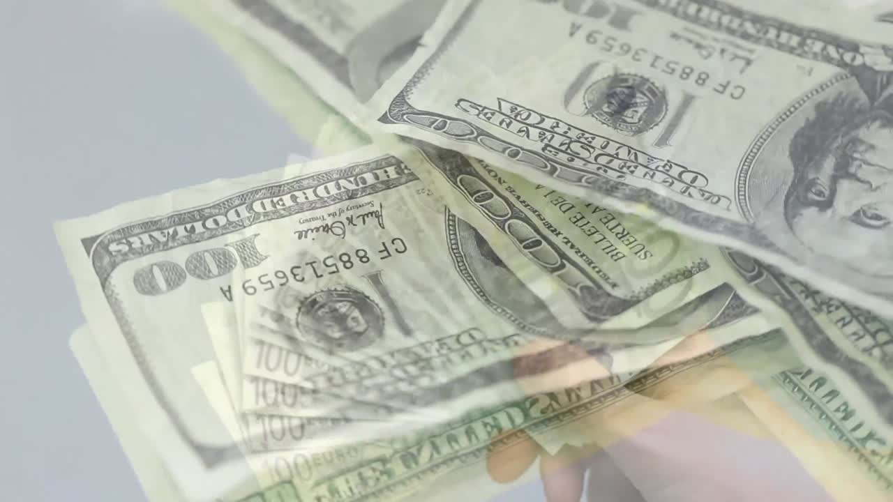 animación de billetes de 100 dólares que caen sobre la mano recortada sosteniendo y sacudiendo billetes de 100 euros.