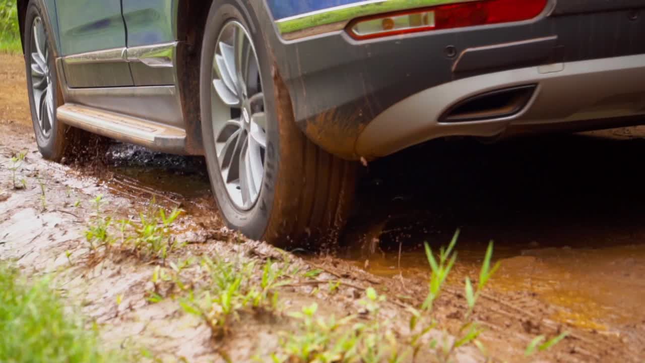 un primer plano de un coche que pasa por un camino de tierra en argentina, navegando a través de un charco de barro