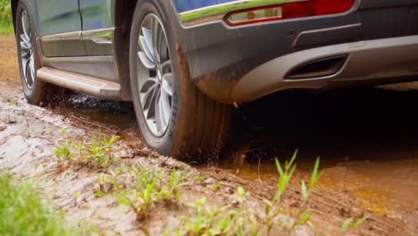 Un-Primer-Plano-De-Un-Automóvil-Que-Pasa-Por-Un-Camino-De-Tierra-En-Argentina,-Navegando-A-Través-De-Un-Charco-De-Barro