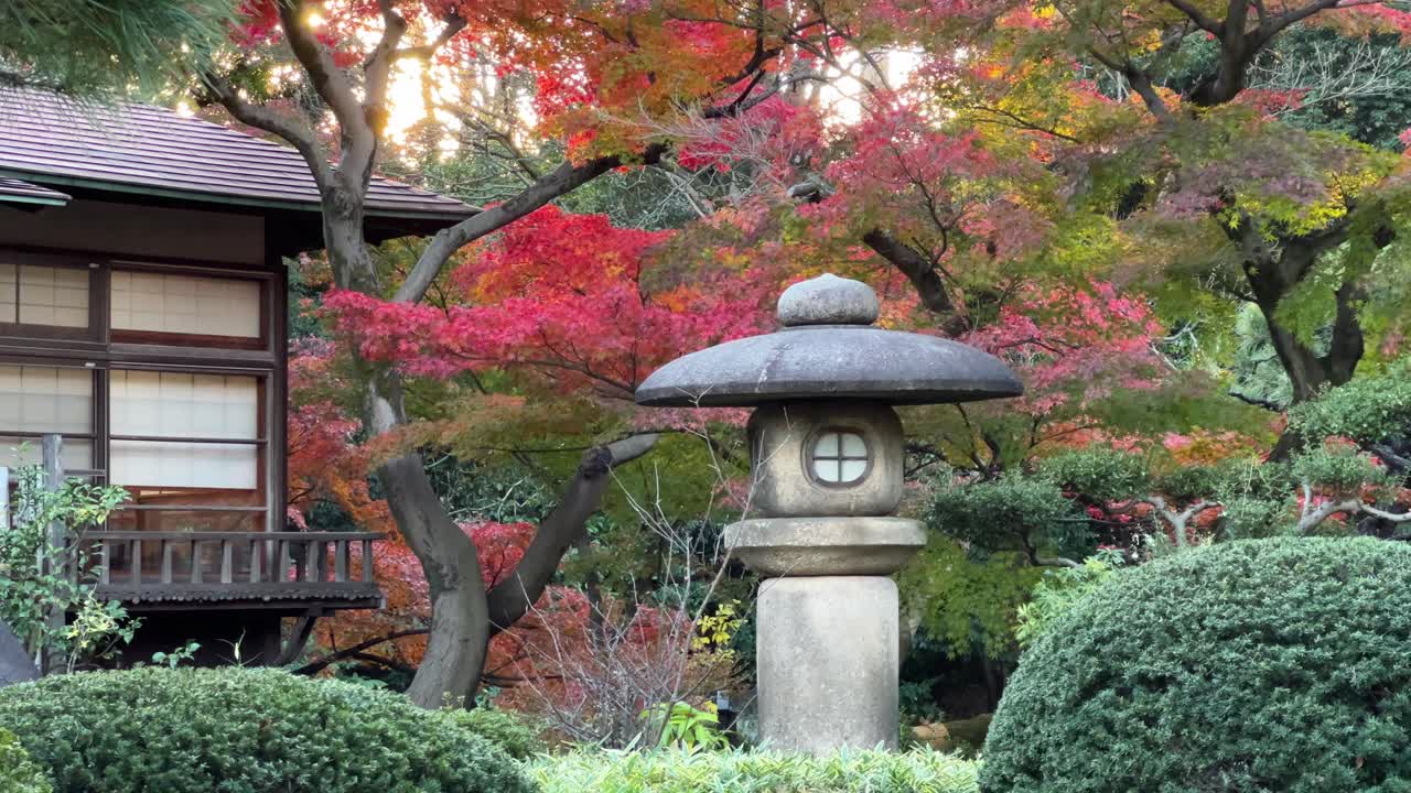 Stunning view inside Japanese landscape garden with waving autumn colors and stone pillar