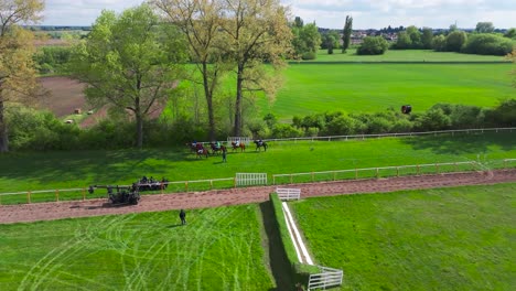 aerial - movie set on green racecourse field with horses and jockeys, czechia