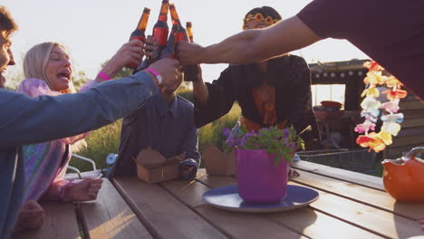 grupo de jóvenes amigos en un festival de música sentados alrededor de la mesa y bebiendo cerveza