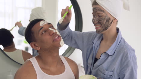 mujer aplicando máscara facial a un apuesto hombre negro 1