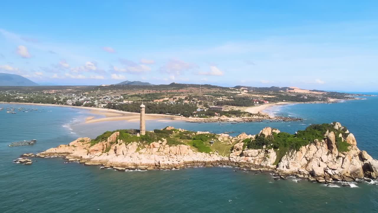 A scenic lighthouse stands on rugged cliffs, guarding a peaceful bay and golden beaches, with charming villages and rolling hills stretching beneath the bright blue sky.