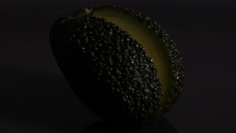 avocado falling and halving against black background