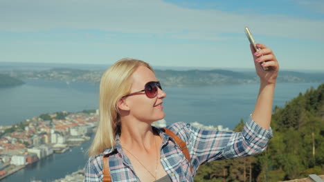 mujer turista tomando fotos de sí misma en el contexto de la ciudad de bergen en la gira de noruega