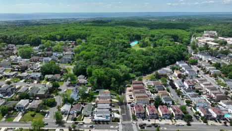 aerial trucking shot of noble neighborhood on staten island with private swimming pool in garden - idyllic greenbelt park in background