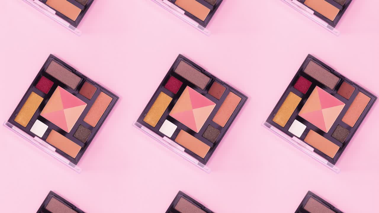 Beauty pattern made of eye shadow palettes with pastel colors rotate on bright pink theme. Stop motion