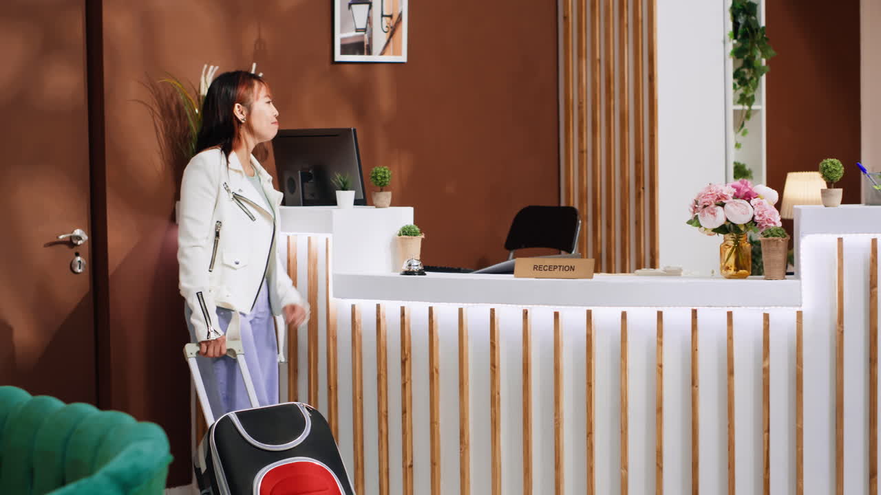 Asian tourist ringing service bell at hotel reception