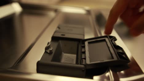 Close-up-shot-of-a-man-inserting-a-detergent-pad-in-the-dishwasher-compartiment