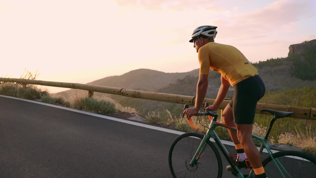 In slow motion, athlete pedaling on a mountain serpentine gazes at the island's scenic view, epitomizing the essence of a healthy lifestyle
