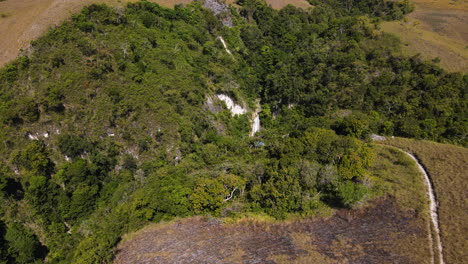 Vista-Aérea-De-Una-Cascada-En-Medio-De-Montañas-Boscosas-En-Sumba,-Indonesia