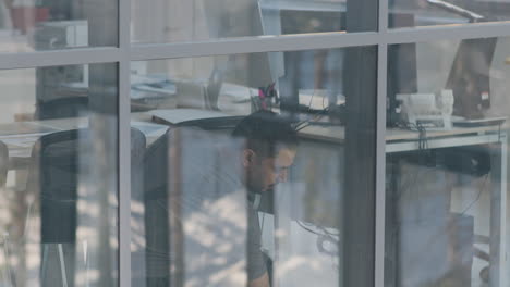 blick von außen auf einen arabischen putzmann, der die fensterscheiben in einem büro reinigt