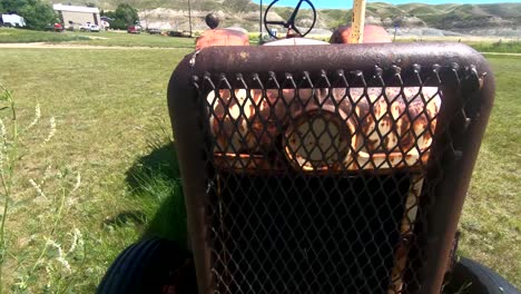 old red rusty tractor sitting in the grass in the country field on a farm near alberta canada