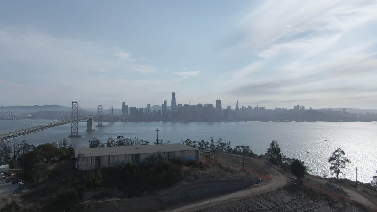예르바 부나 섬과 보물 섬 위의 공중 비행은 샌프란시스코의 스카이 라인과 베이 브릿지를 북부 캘리포니아의 흐릿한 여름 구름이 많은 오후에 드러니다. - 4k - 평평한 색상
