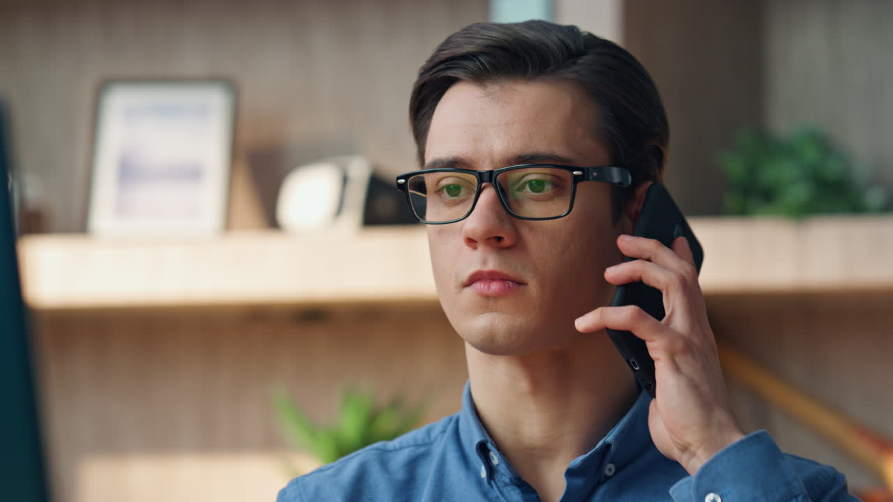 사무실에서 휴대전화 통화에 응답하는 심각한 남자. 스마트폰으로 전화하는 남자