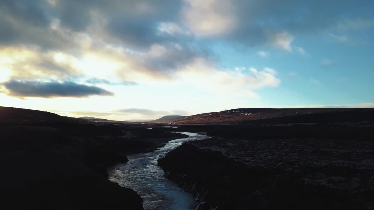 Drone with cinematic movements shows beautiful icelandic waterfall, Hraunfossar, in sunset light from multiple angles