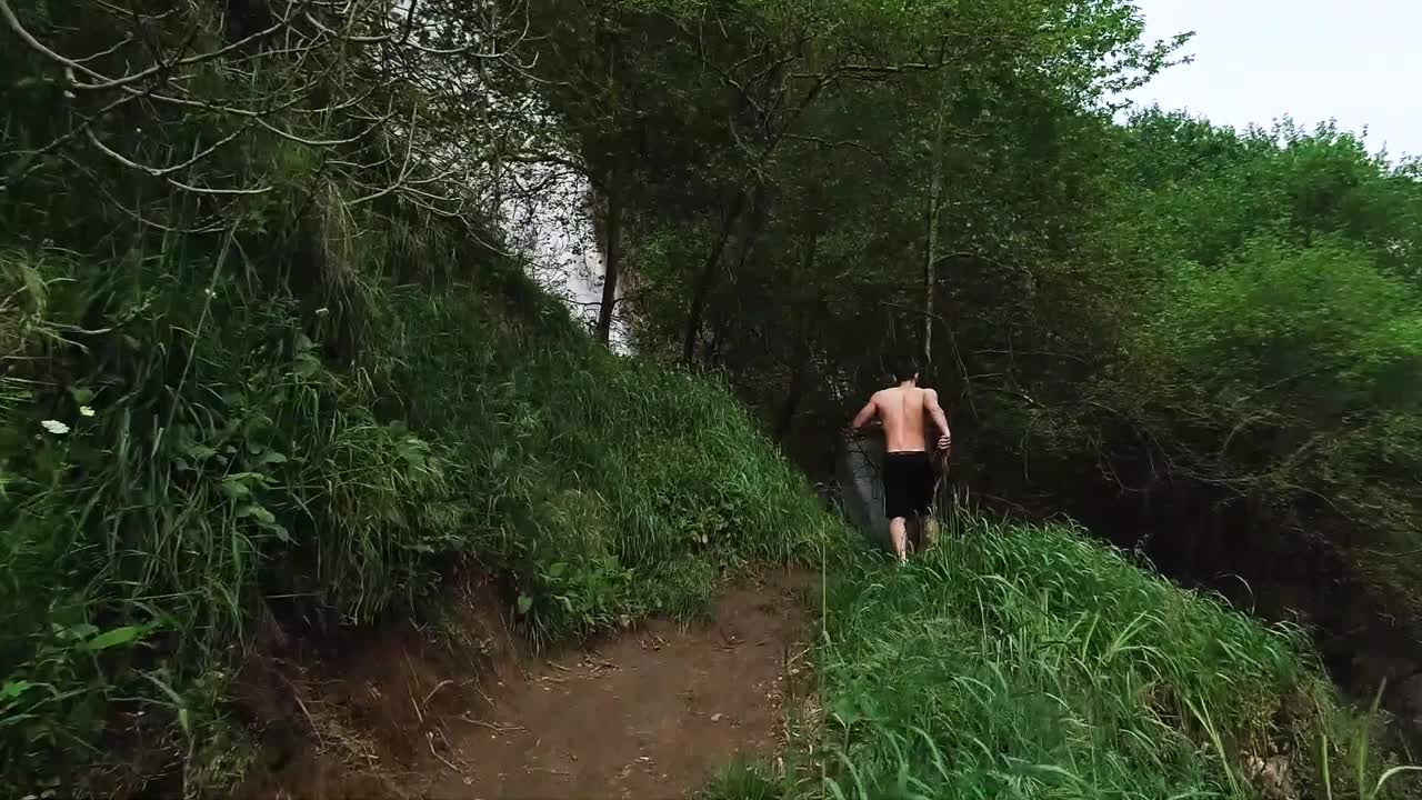 Young Caucasian man runs on dirt hiking path towards Kfarhelda river and waterfall