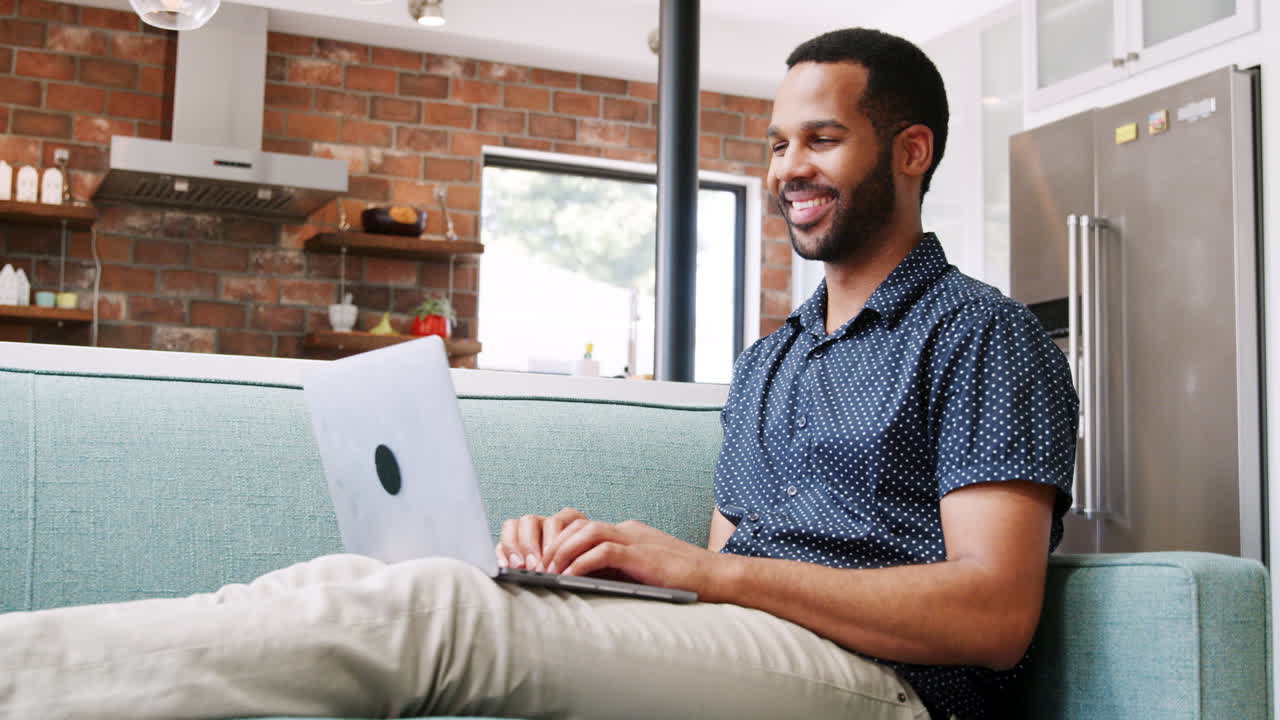 Man Relaxing On Sofa At Home Watching Movie On Laptop Computer