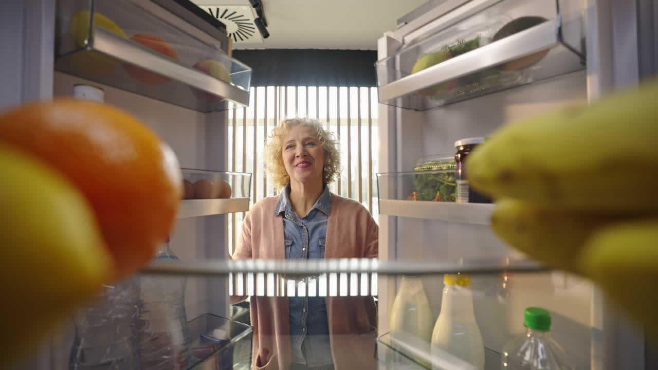 Woman reaching into refrigerator for fruit