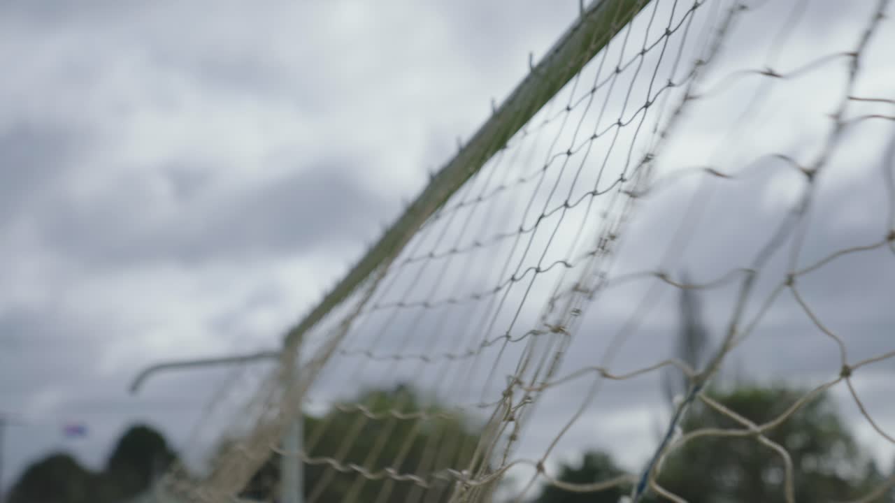 Graceful football kicked into goal captured in closeup slow motion on cloudy day