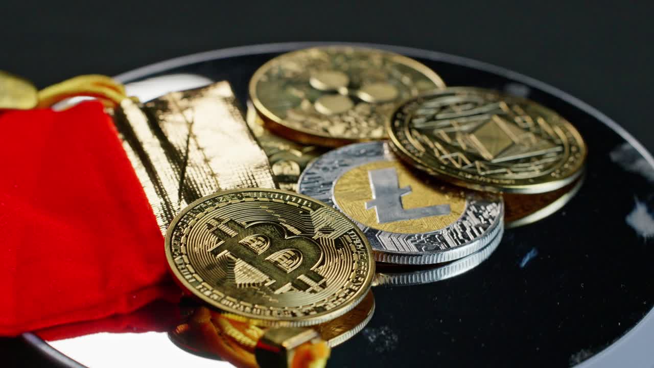 Shiny coins representing bitcoin, ripple, litecoin, and ethereum cryptocurrency turning slowly on silver turntable.