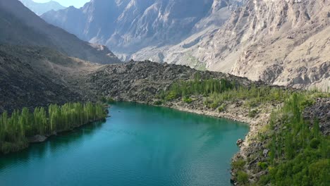 aerial drone of a unique glacier blue lake called upper kachura lake, surrounded by a green forest in the mountains of skardu pakistan on a sunny summer day