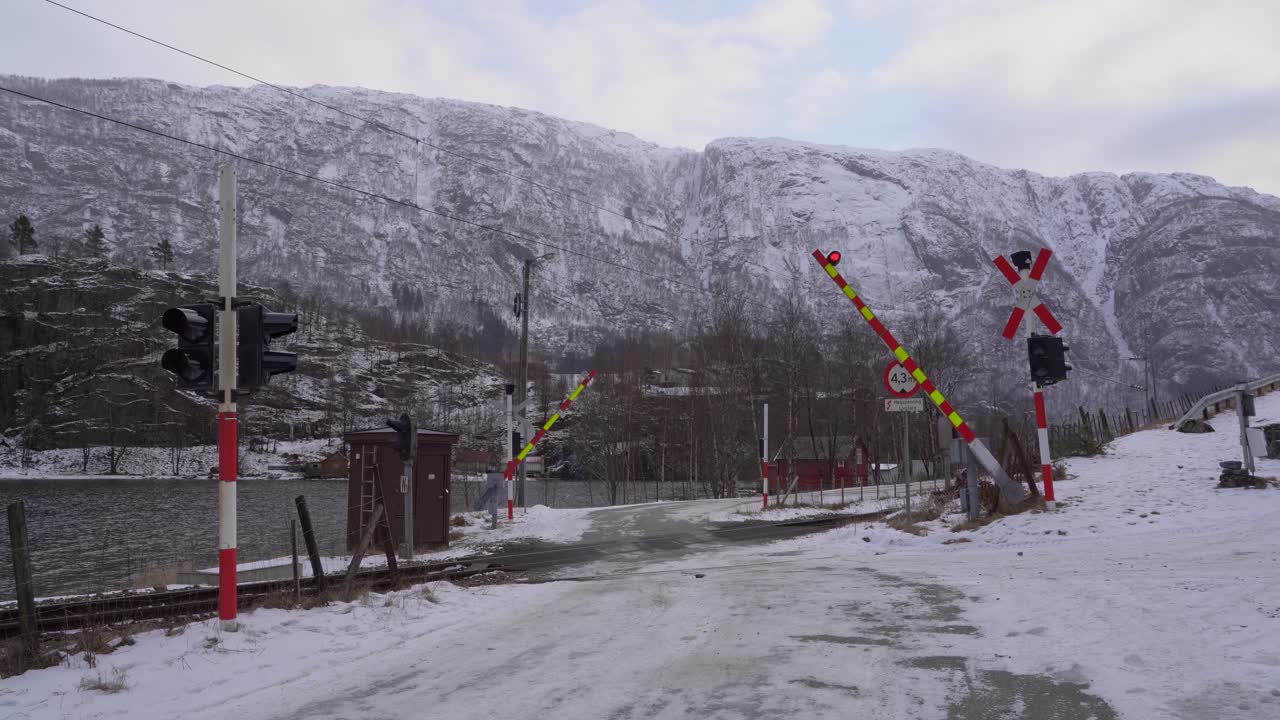 Hemzemin geçitte gelen treni uyarmak için kapanan bariyerler ve yanıp sönen ışıklar - Uyarı ışıkları - Karlı Norveç havası