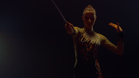 Girl-performing-with-flying-ribbon-for-camera.-Gymnast-rehearsing-in-dark-hall.