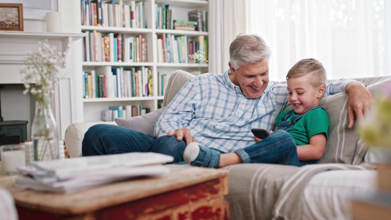 Grandfather and Grandson Using a Smartphone Together on the Sofa