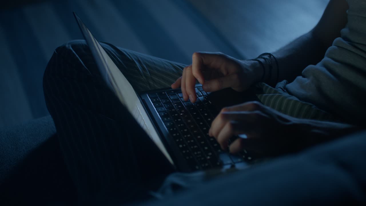Person typing on a laptop at night