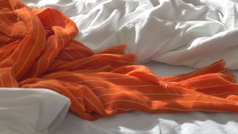 messy bed with orange blanket