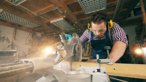 male carpenter is processing wood with a rotary saw