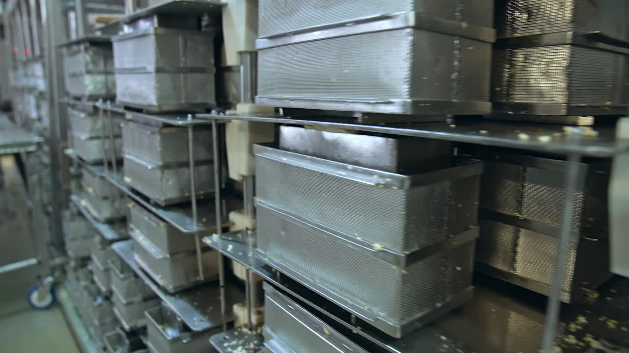 Numerous stainless steel containers for butter. Steel reticulated boxes for butter stored on the tall metal shelves. Modern dairy enterprise.