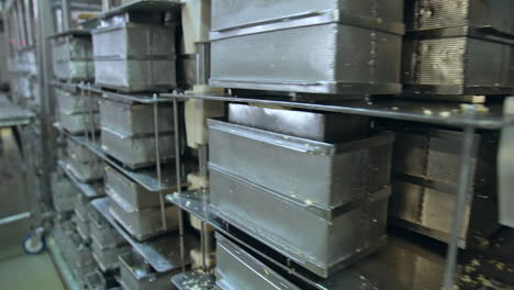 numerous stainless steel containers for butter. steel reticulated boxes for butter stored on the tall metal shelves. modern dairy enterprise.