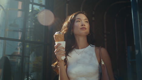 una mujer sonriente disfrutando de helado al aire libre. una dama asiática morena comiendo postre.