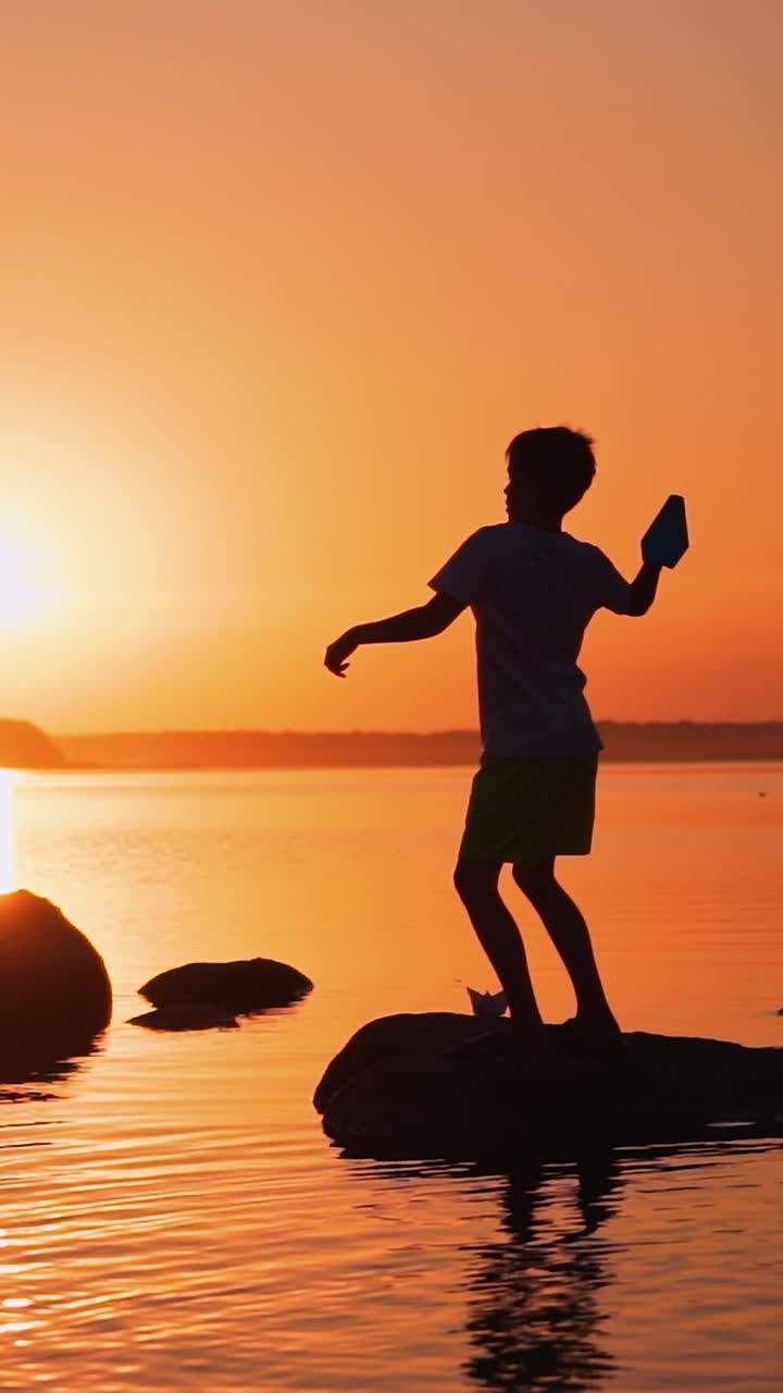 Little boy with paper plane. Beautiful sunset. Origami. Vertical video