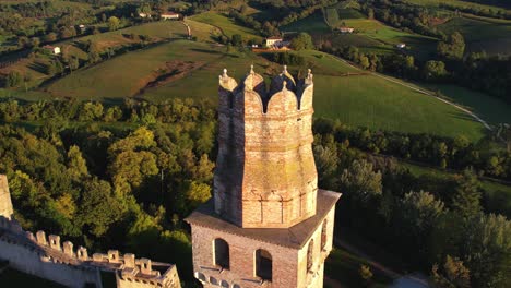 aerial view over a medieval castle tower on top of a hill, surrounded by prosecco vineyards, in italy