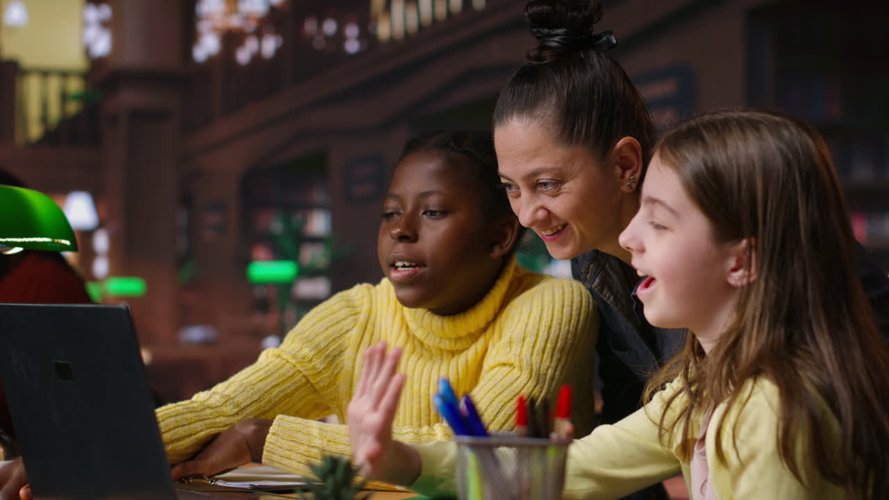 Students learning together in a library using a laptop