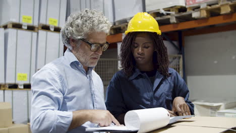 focused caucasian boss and female african american worker talking in warehouse