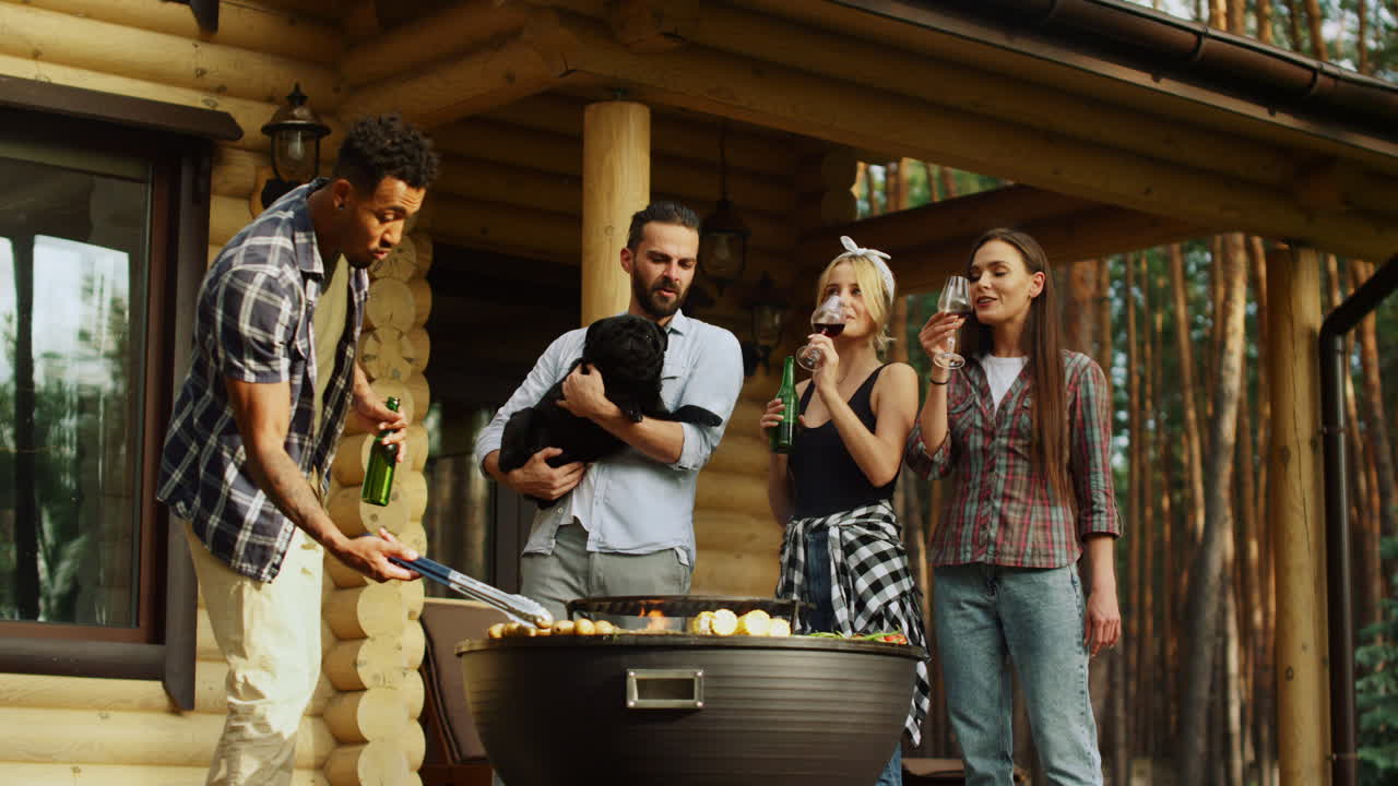 hombre afroamericano cocinando verduras al aire libre. mujeres hermosas bebiendo vino